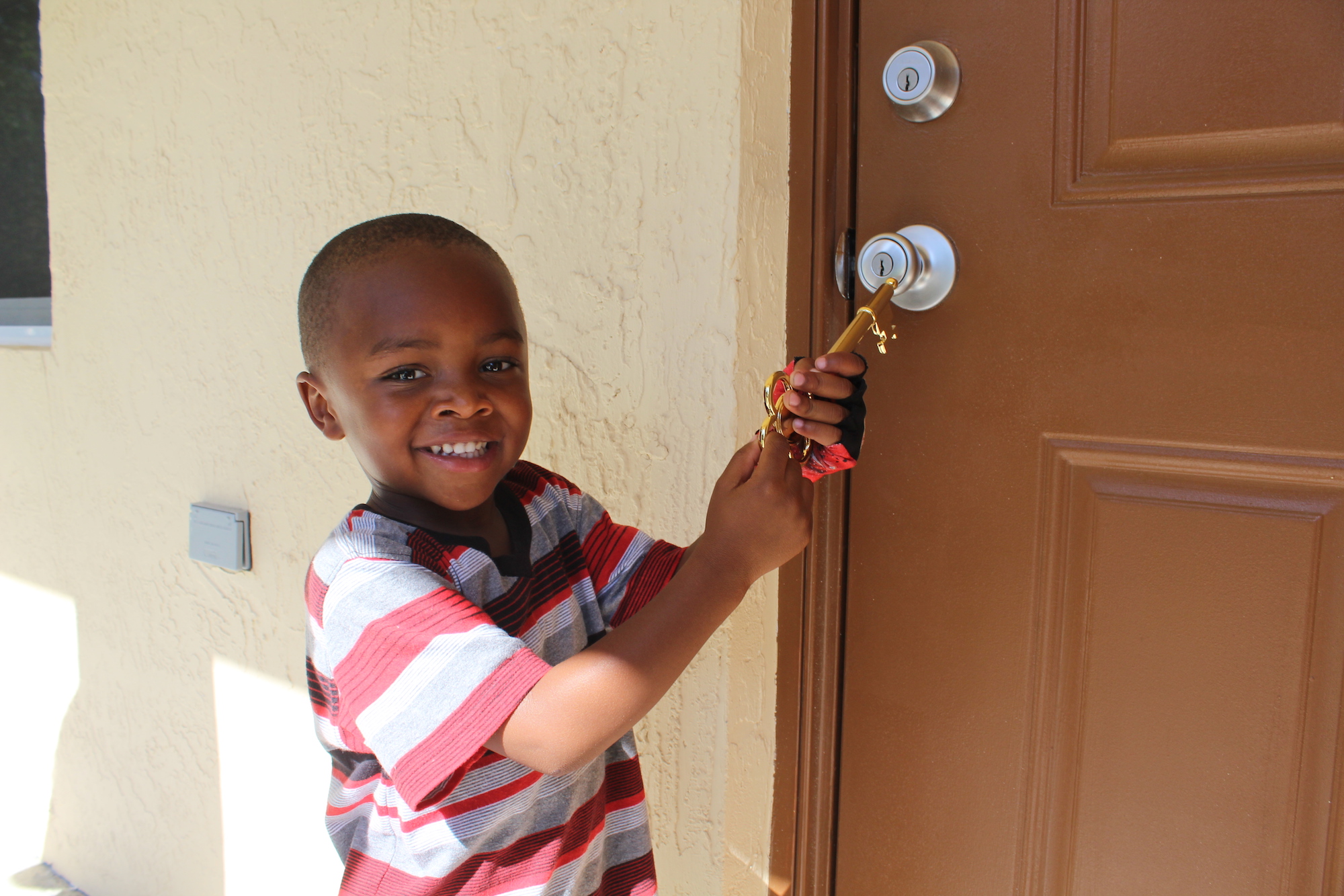 little boy holding key at front door of new home. little boy holding key at front door of new home.