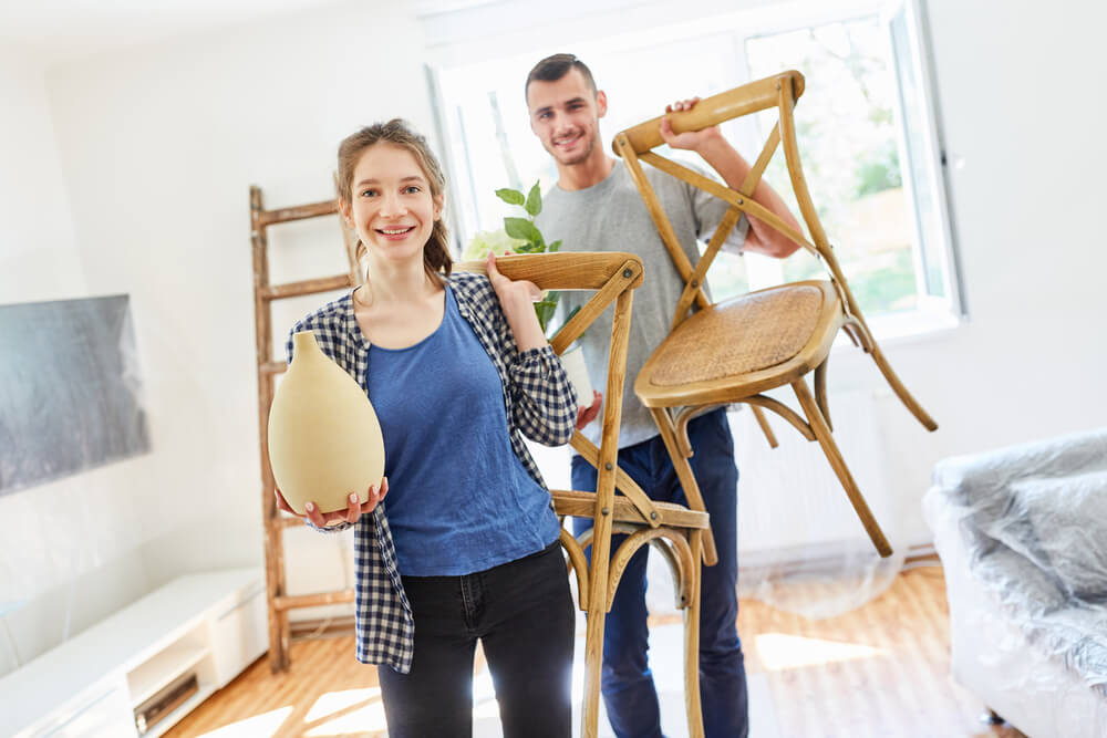 Young Couple With Chairs and Plants Moving in and Setting up the New Apartment