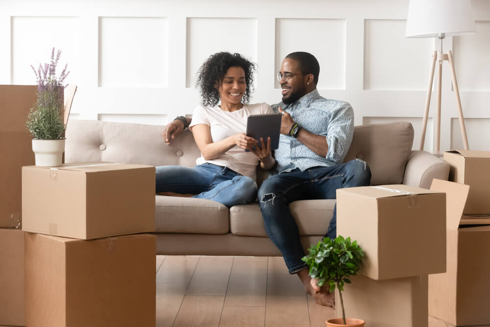 Happy Couple Husband and Wife Sit On Sofa With Boxes